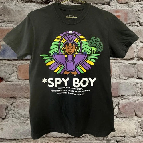 Black mardi gras t-shirt with 'Spy Boy' graphic design on a brick wall background