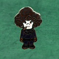 Metallic character enamel pin by Compton III, a New Orleans artist with curly hair on a green background 